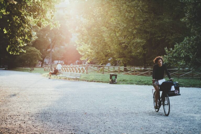 ragazza in bici su strada di ghiaia in parco cittadino